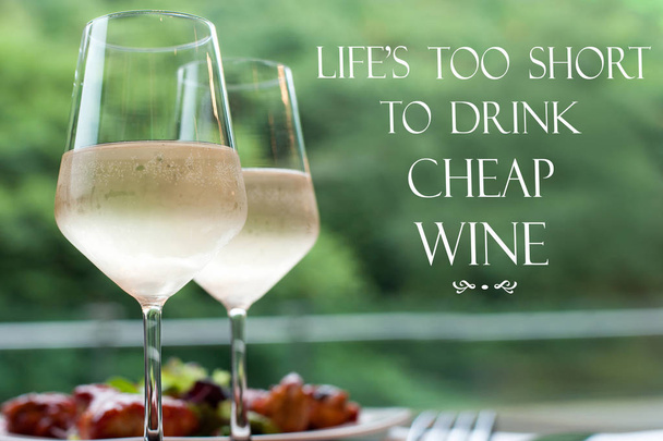Life is too short to drink cheap wine-two glasses of delicious white wine. Inspirational motivation quote. Horizontal image/ poster with vintage filter - 写真・画像