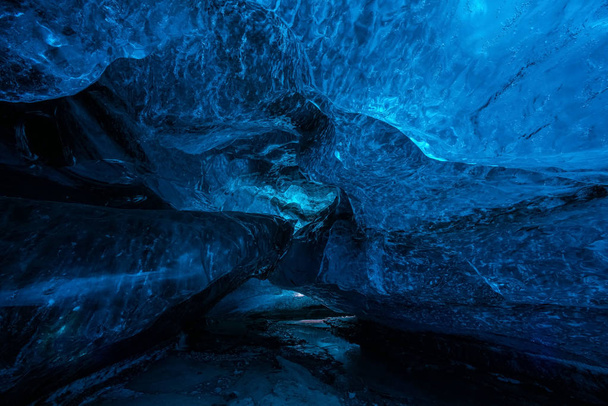 Ledové jeskyně nebo jeskyně Crystal v islandské ledovce jsou opravdu okouzlující zázrak přírody. Ledovcové modré prosklené odfoukne a vytváří úžasné jeskyně. Tekoucí voda a černým pískem. - Fotografie, Obrázek