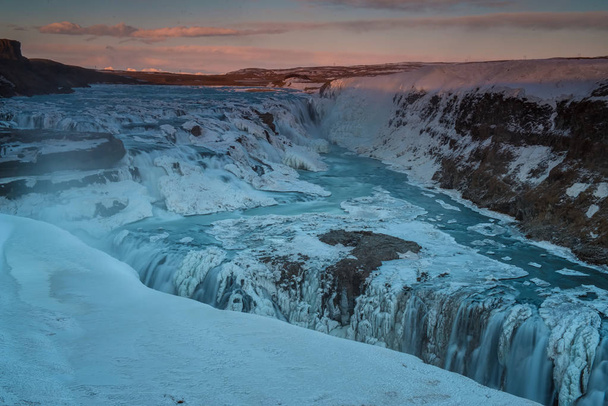 La cascade gelée de Gullfoss avec des nuages dorés dans le ciel. L'eau qui coule est captée par une longue exposition. Superbe couleur bleue de l'eau du glacier. Environnement naturel et hivernal
. - Photo, image
