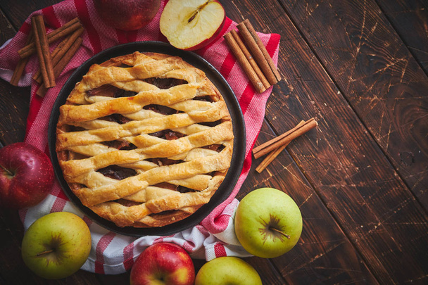 Homemade pastry apple pie with bakery products on dark wooden kitchen table - 写真・画像