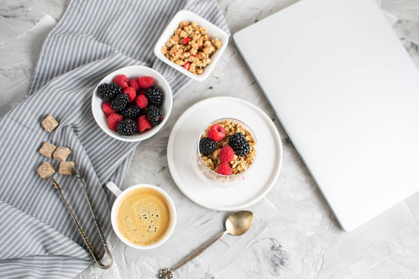 Gezond ontbijt kopje koffie Griekse yoghurt met zelfgemaakte Granola, bessen, frambozen en bramen werk Laptop ochtend Concept - Foto, afbeelding