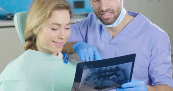 video of dentist doctor man showing x-ray to woman - Felvétel, videó