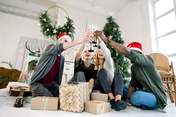 Grupo multiétnico de amigos comemorando o Ano Novo e brindando com copos de champanhe em casa
 - Foto, Imagem