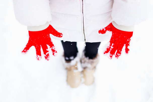 schöne rote Handschuhe in einem Mädchen, das in Winterkleidung gekleidet war. Auf den Handschuhen liegt Schnee - Foto, Bild