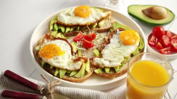 Delicioso desayuno saludable con sándwiches de aguacate en rodajas con huevo frito - Imágenes, Vídeo