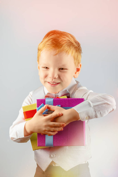 5 歳の幸せな赤髪少年彼の手に 2 つのギフトを押しながら笑みを浮かべて - 写真・画像