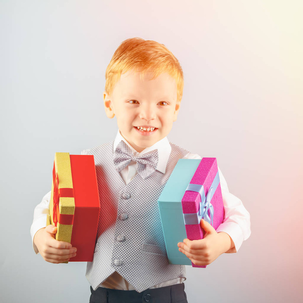 Five year old happy red-haired boy holding two gifts in his hands and smiling - Φωτογραφία, εικόνα