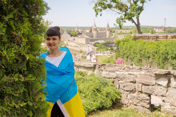 La fille enveloppa le drapeau de l'ukraine. Sur le fond de la forteresse Kamyanets-Podilsky
. - Photo, image