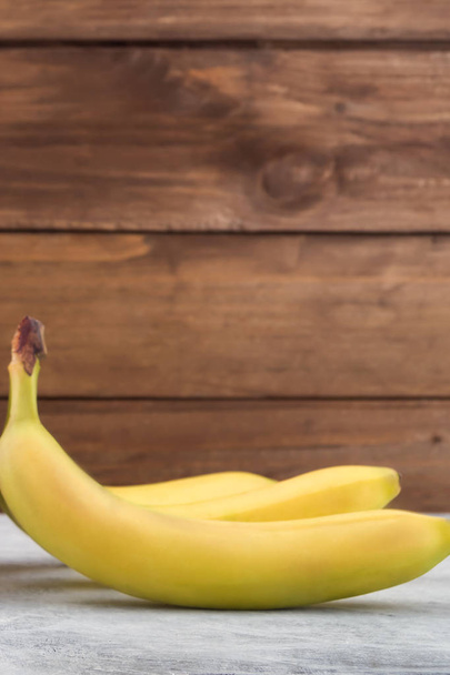 Zralé banány v kůži. Dřevěné pozadí. Vertikální. - Fotografie, Obrázek