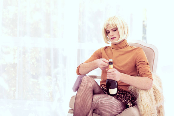 TITLE: Fashionable young transgender taking bung from wine bottle - Photo, image