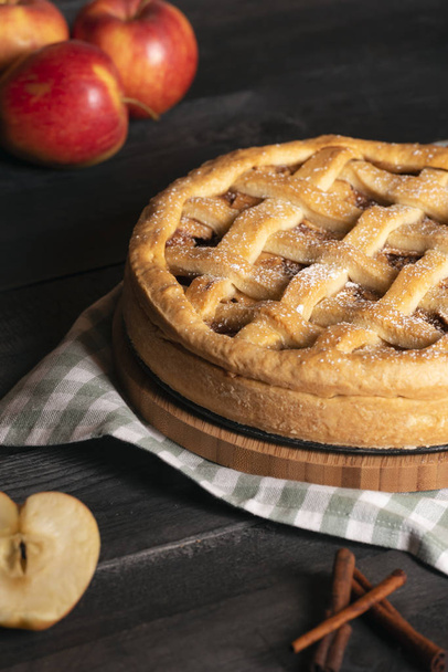 Házi készítésű finom almás pite fahéj és őrölt cukor, meg a konyhai törölköző, egy rusztikus tábla és az apple gyümölcs. Fogyasztásra kész édes ételek. - Fotó, kép