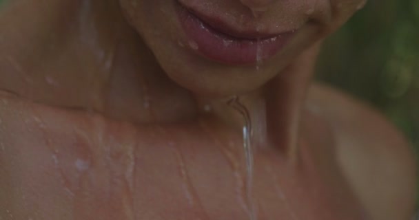 young beautiful girl in nature washes under a natural shower in a tropical waterfall of warm and transparent water. concept of well-being and purity, travel and tropical places - Footage, Video