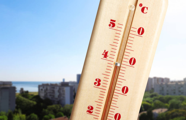 Extreme high temperature on thermometer and cityscape view - Photo, Image