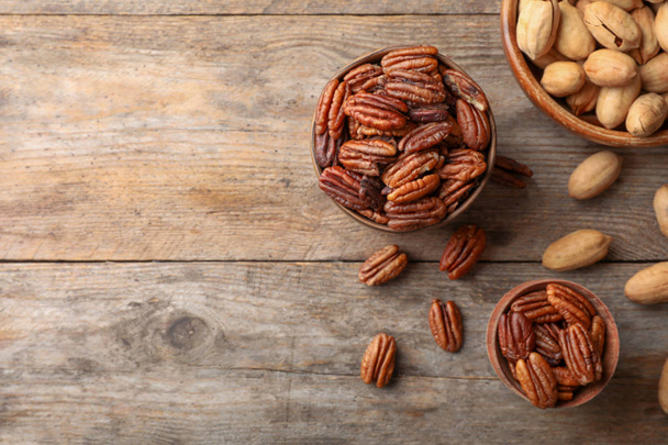 Flat lay composition with tasty pecan nuts on wooden table. Space for text - Zdjęcie, obraz