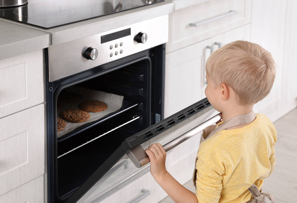 Little boy baking cookies in oven at home - Valokuva, kuva