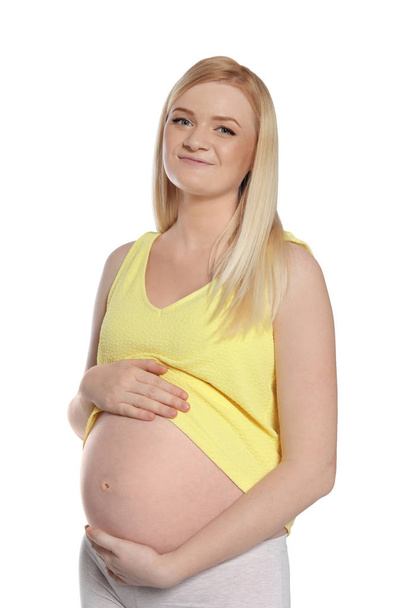 Mooie zwangere vrouw toont haar buik op witte achtergrond - Foto, afbeelding