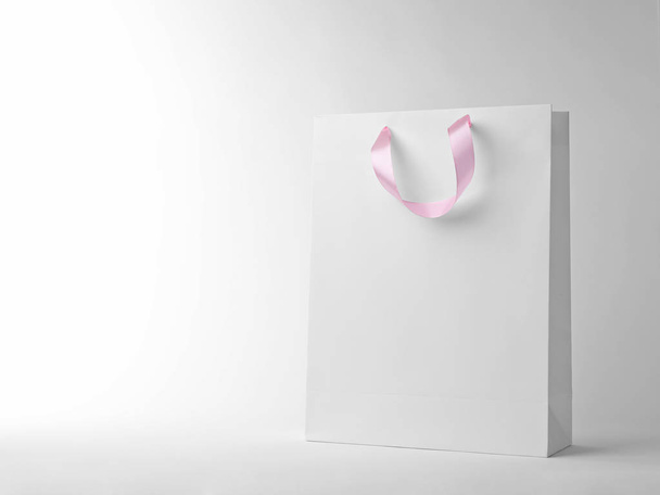 Paper shopping bag with ribbon handles on white background. Mockup for design - Foto, Imagen