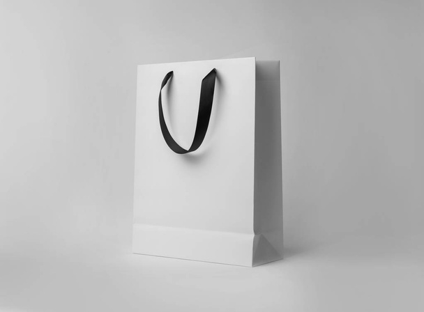 Paper shopping bag with ribbon handles on white background. Mockup for design - Photo, image