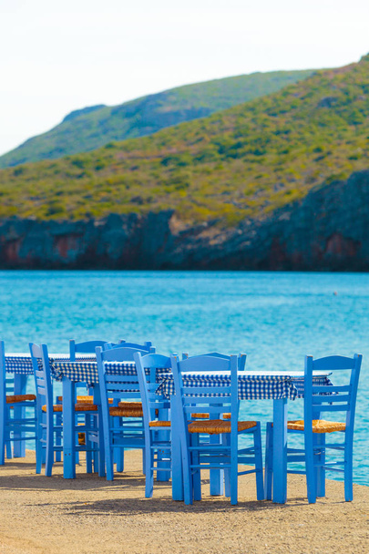 Seaside blue table and chairs open cafe outdoor restaurant in Greece on sea shore. Summer vacation on resort. - Fotoğraf, Görsel