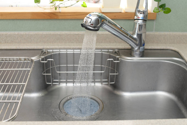 Küchenarmatur und Spüle aus Edelstahl mit fließendem Wasser - Foto, Bild