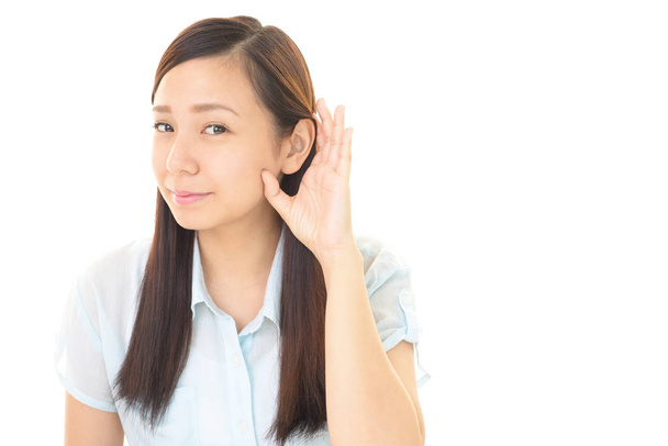 Eine Frau legt ihre Hand auf ihr Ohr - Foto, Bild