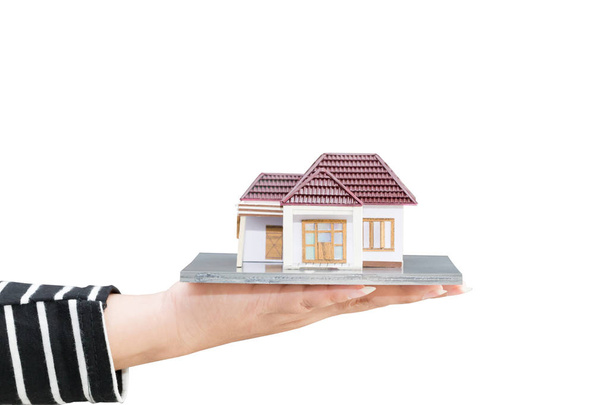 Woman hand holding home model on white background. Loan and real estate concept - Photo, Image