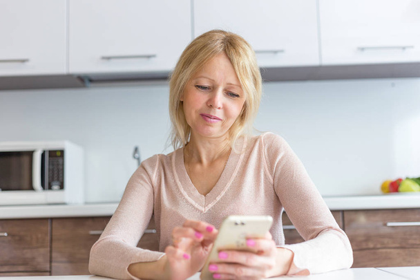 serious middle age businesswoman using a smartphone at home - Foto, imagen