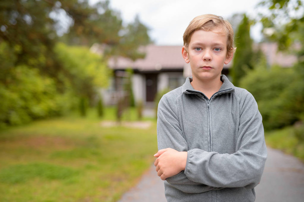 Portret van de jonge knappe jongen met blond haar huis in de open lucht - Foto, afbeelding