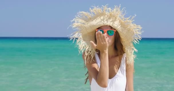video of woman wearing white summer hat, waving hello and blowing kiss while standing in sea water  - Materiaali, video
