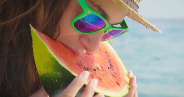 video of woman in hat and sunglasses eating fresh sweet watermelon slice at blue sea  - Footage, Video