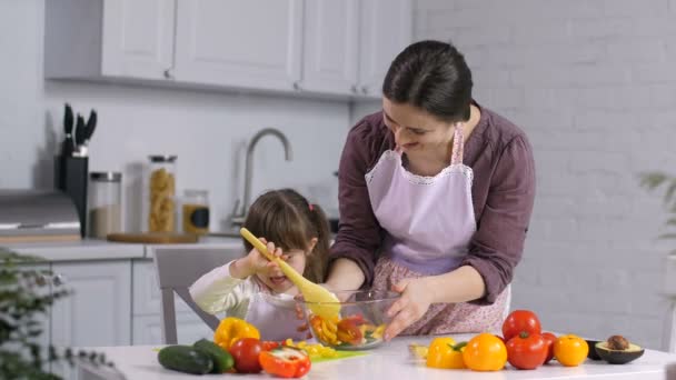 Meisje met speciale behoeften helpt moeder voorbereiding salade - Video