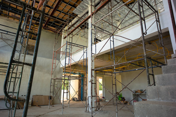 Perspektiva uvnitř domu ve výstavbě s instalací izolant a elektřiny. Konstrukce ocelová lešení na stavbě - Fotografie, Obrázek