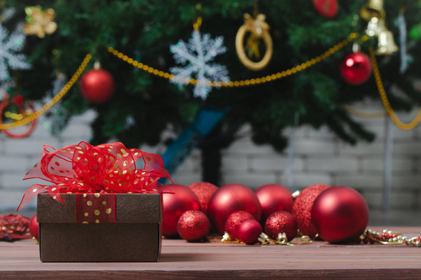 Una bella scatola regalo rossa lucida, ornamenti natalizi decorati bordo, copiare lo spazio in tavola di legno medio e fiocco di neve
. - Foto, immagini