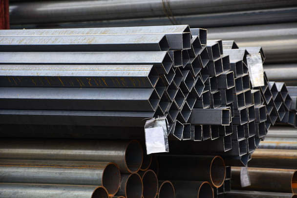 Metal rolling. A round and square tube with labels for text are stacked in storage for sale and loading in stock in the open air. Close-up. - Photo, Image