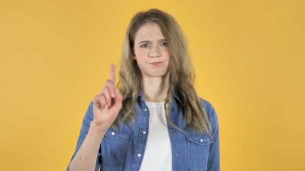 Mladá hezká holka mává prst odmítnout na žlutém podkladu - Záběry, video