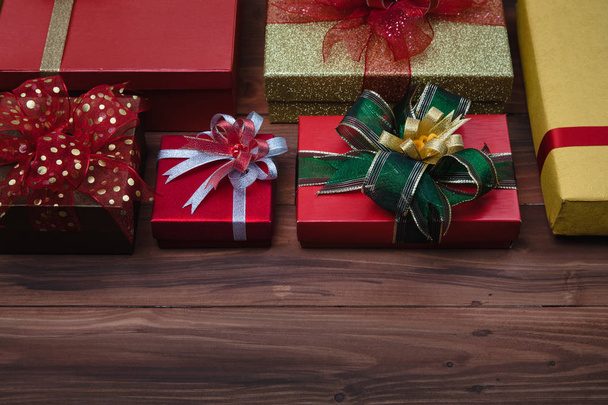 Detailní záběr záběr žluté, zlaté, červené dárkové krabičky s colorfull stuha na dřevěné pozadí, koncept pro vánoční pozdrav oslavu. Volné místo kopírování. - Fotografie, Obrázek