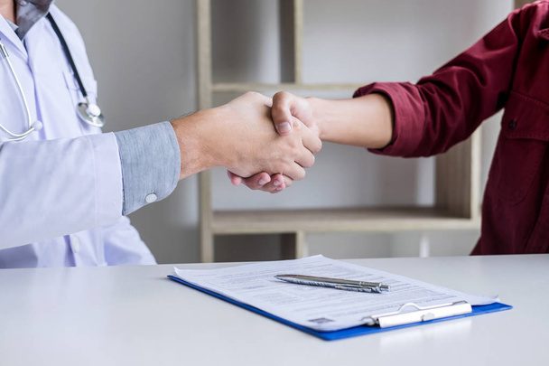 Professional Male doctor in white coat shaking hand with female patient after successful recommend treatment methods, Medicine and health care concept. - Photo, image