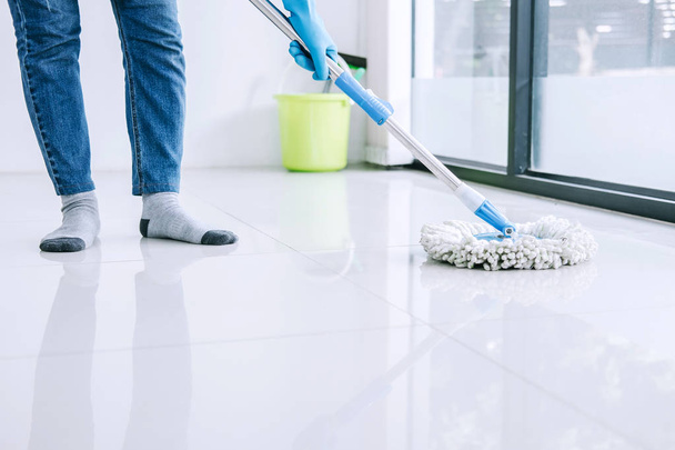 Housekeeping and cleaning concept, Happy young woman in blue rubber gloves wiping dust using mop while cleaning on floor at home. - Photo, image