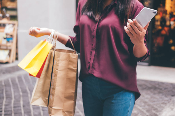 Consumerism, shopping, lifestyle concept, Young woman holding colorful shopping bags and smartphone enjoying in shopping. - Foto, Bild