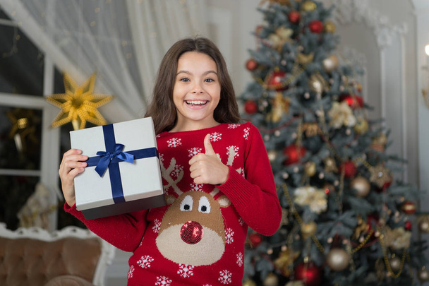 little child girl likes xmas present. Christmas. Kid enjoy the holiday. Happy new year. small happy girl at christmas. The morning before Xmas. New year holiday. thumb up. The best present - Foto, Imagen