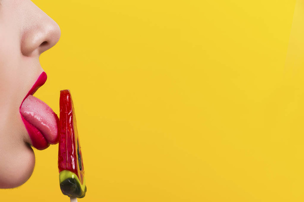 lèvres rouges de profil avec une image de bonbons sur un fond jaune avec espace pour le texte
 - Photo, image