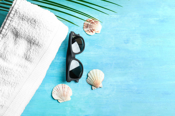 Sunglasses with towel and seashells on color background - Fotó, kép