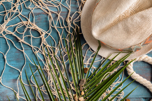 Composition with hat and palm leaf on color wooden background - Fotoğraf, Görsel