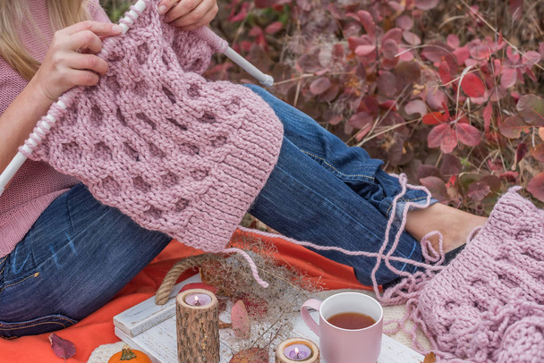 hands of girl knitting with knitting needles in the autumn garden. Knitting process. Cozy tranquil garden setting. - Zdjęcie, obraz
