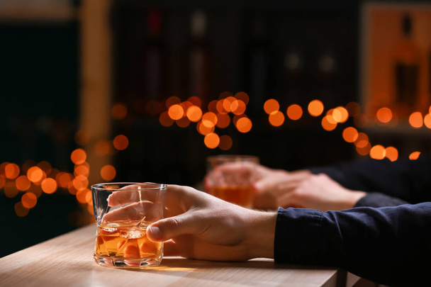 Man with glass of whiskey at wooden table in bar - Φωτογραφία, εικόνα