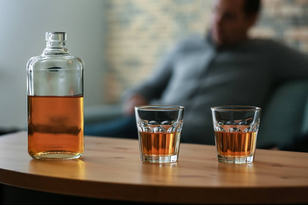 Γυαλιά και ένα μπουκάλι ουίσκι στο ξύλινο τραπέζι - Φωτογραφία, εικόνα
