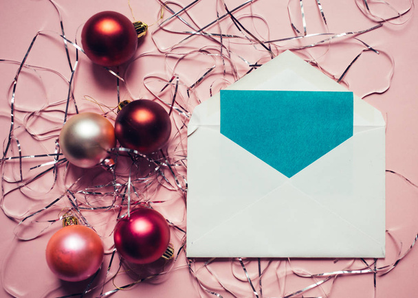 Christmas composition. Envelope with a card. Christmas red and pink decorations on pink background. - Foto, imagen