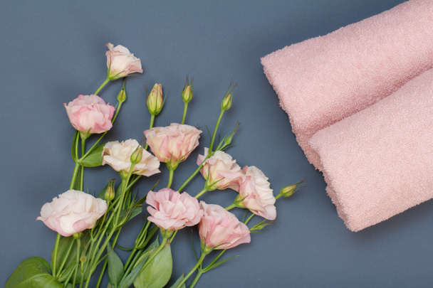 Toallas suaves de rizo con ramo de rosas rosadas sobre fondo gris. Vista superior
. - Foto, imagen