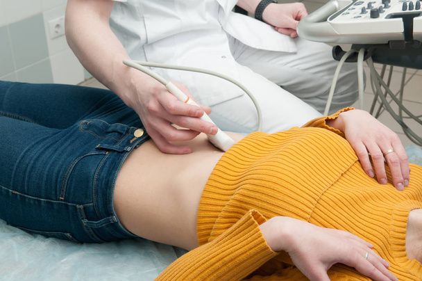 Fechar a mão de um médico com sensor de ultra-som no estômago da mulher no hospital
 - Foto, Imagem