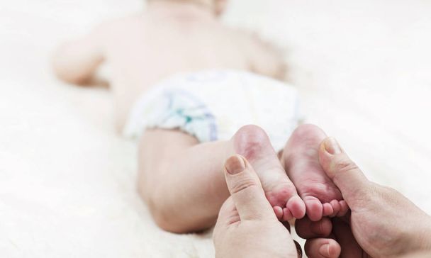 母が作る幸せな赤ちゃんのためのマッサージ、白の背景に、足にオイルを適用 - 写真・画像